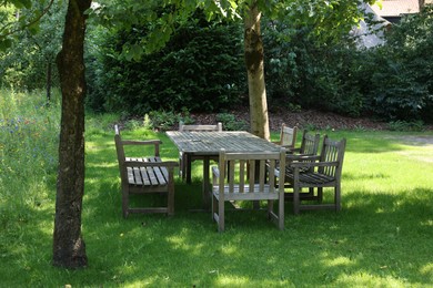 Empty wooden table with bench and chairs in garden