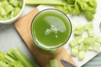 Photo of Glass of delicious celery juice and vegetables on grey table, above view