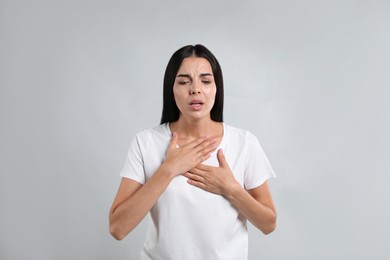 Photo of Young woman suffering from breathing problem on light background