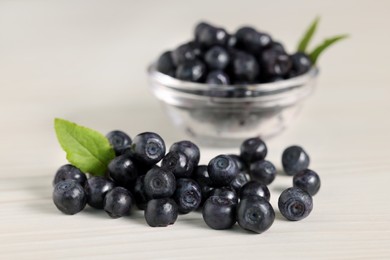 Photo of Ripe bilberries and leaves on white wooden table, closeup