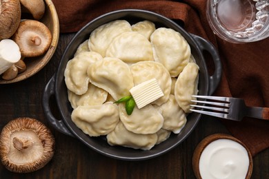 Photo of Serving pan of delicious dumplings (varenyky) with mushrooms on wooden table, flat lay