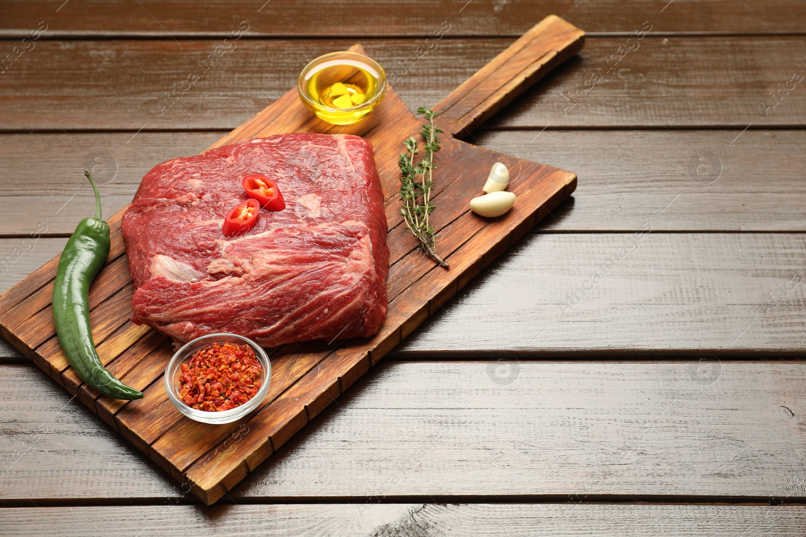 Photo of Fresh raw beef cut, spices and oil on wooden table. Space for text