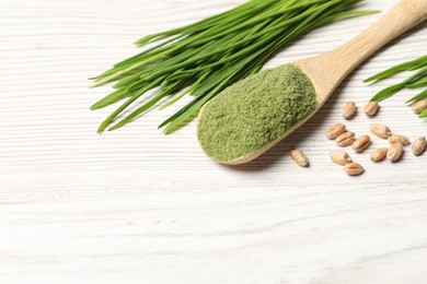 Photo of Wheat grass powder in spoon, seeds and fresh sprouts on white wooden table, space for text