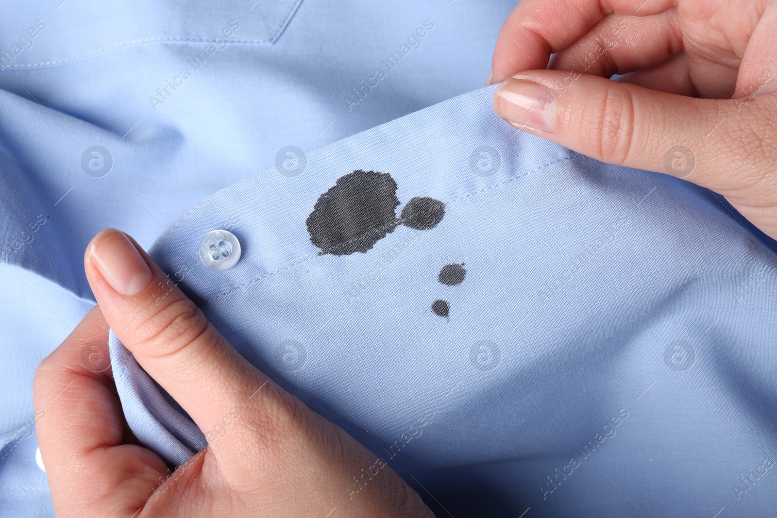 Photo of Woman holding shirt with black ink stain, closeup