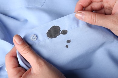 Woman holding shirt with black ink stain, closeup