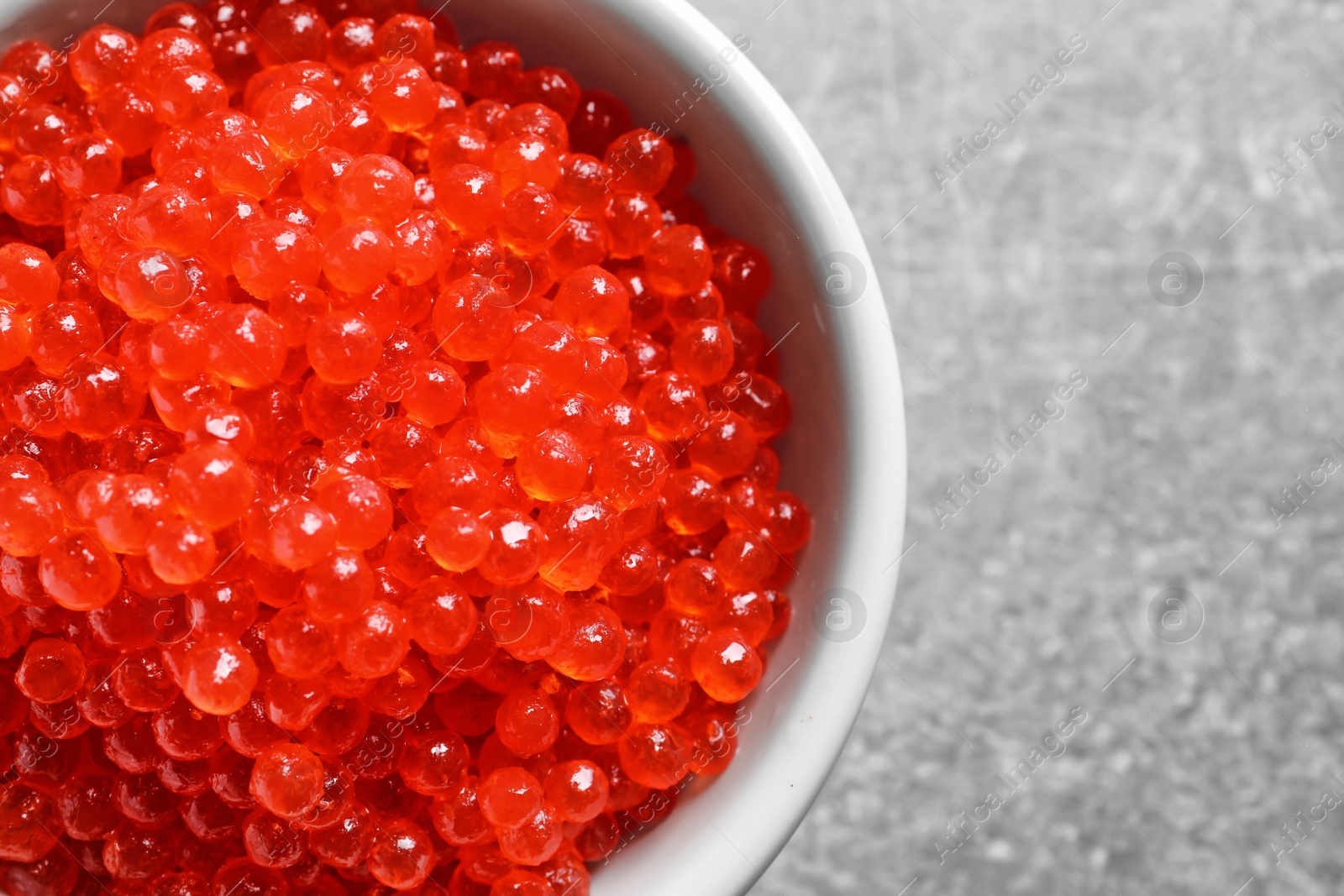 Photo of Ceramic bowl with delicious red caviar on table, closeup