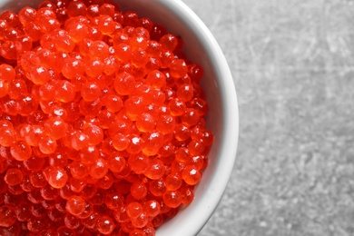 Photo of Ceramic bowl with delicious red caviar on table, closeup