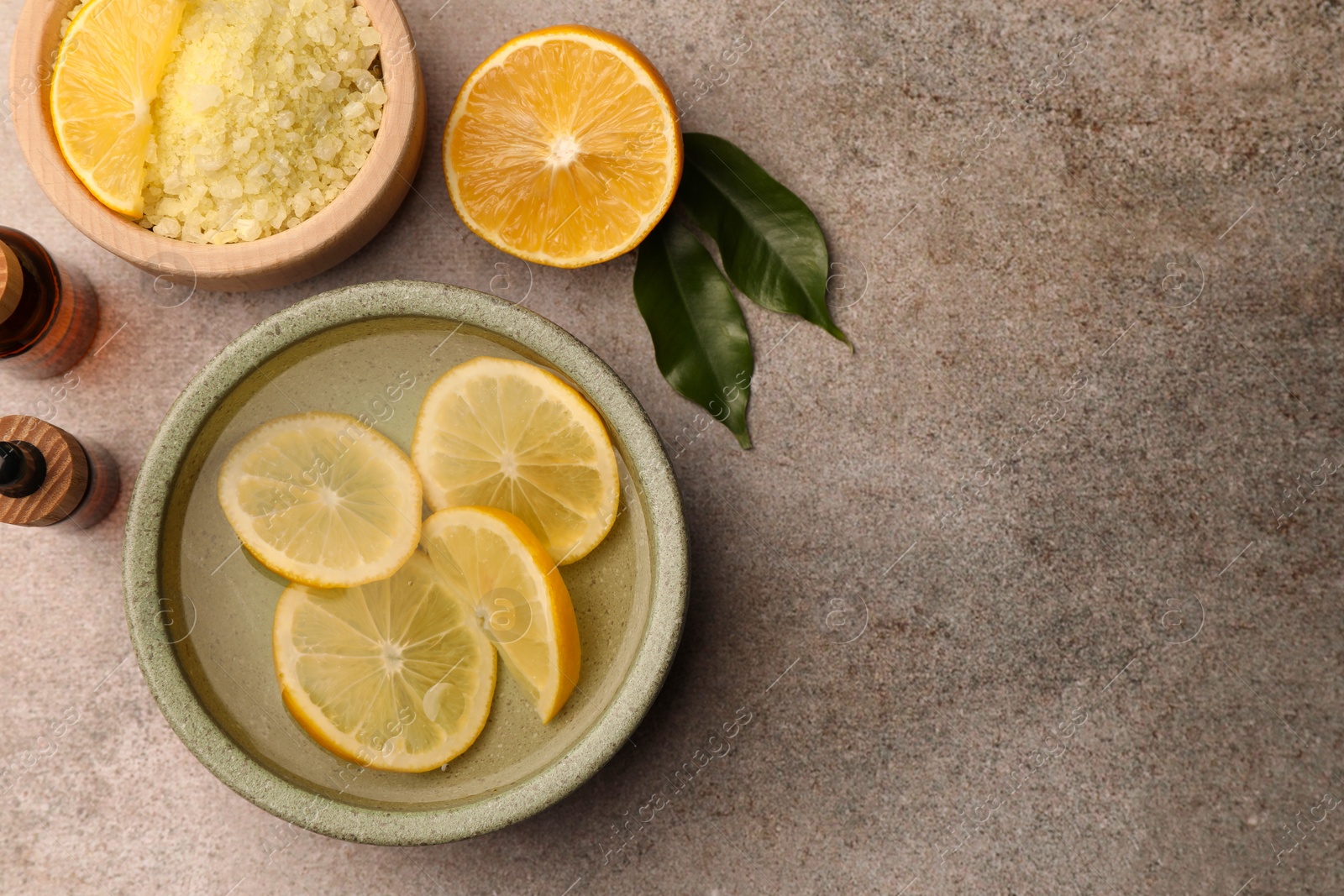 Photo of Flat lay composition with essential oil and lemons on grey textured table, space for text. Aromatherapy treatment