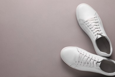 Pair of stylish white sneakers on grey background, top view. Space for text