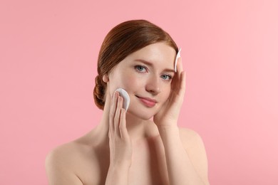 Photo of Beautiful woman with freckles wiping face on pink background