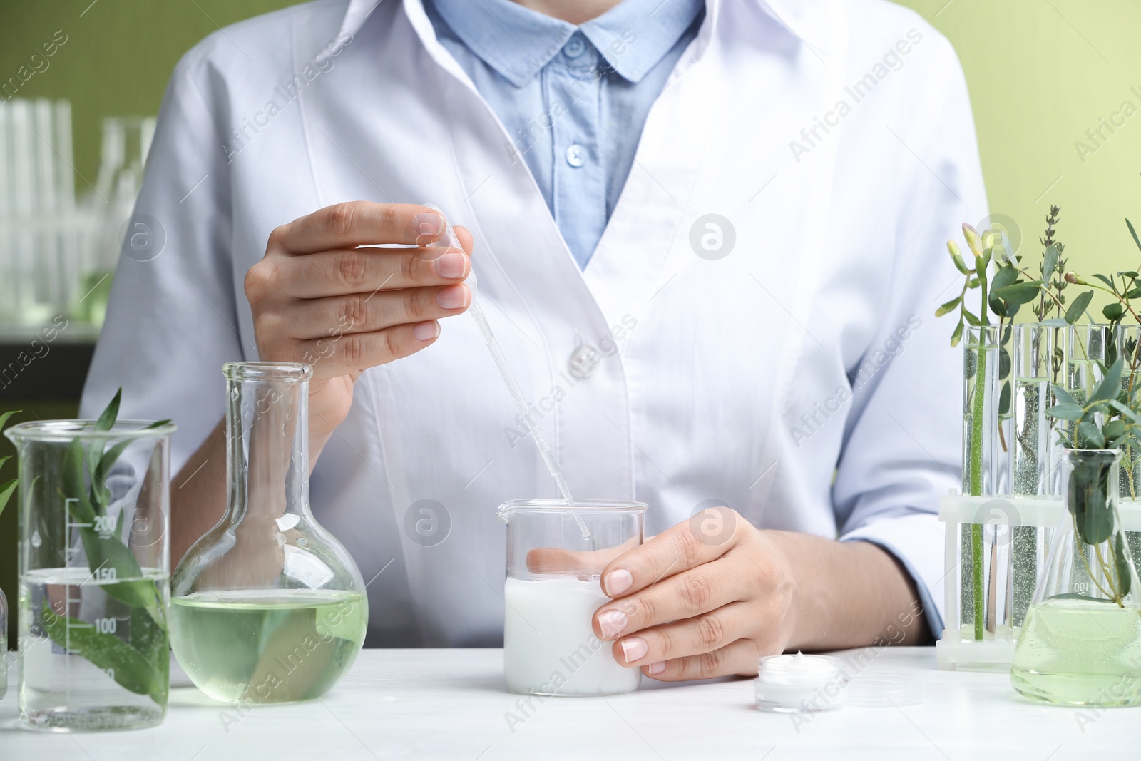 Photo of Woman working with cream at table in cosmetic laboratory, closeup