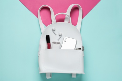 Stylish backpack with accessories and smartphone on color background, top view