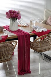 Photo of Pink peonies on table with beautiful setting and rattan chairs in dining room