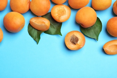 Photo of Delicious ripe sweet apricots on blue background, flat lay. Space for text