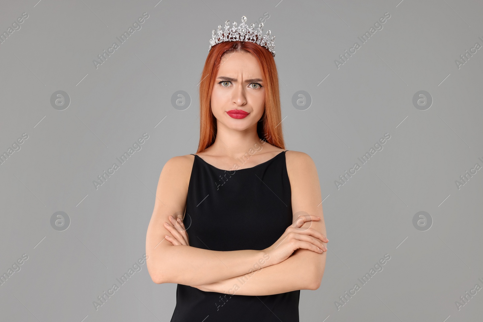 Photo of Emotional young woman with tiara in dress on light grey background