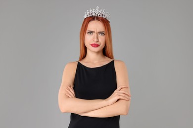 Photo of Emotional young woman with tiara in dress on light grey background