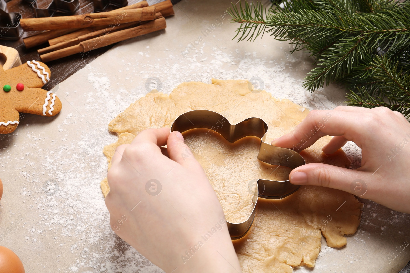 Photo of Woman making Christmas cookie with cutter at table, closeup