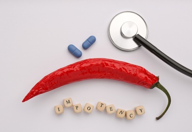 Flat lay composition of chili pepper and cubes with word Impotency on white background