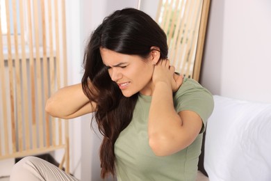 Young woman suffering from neck pain at home