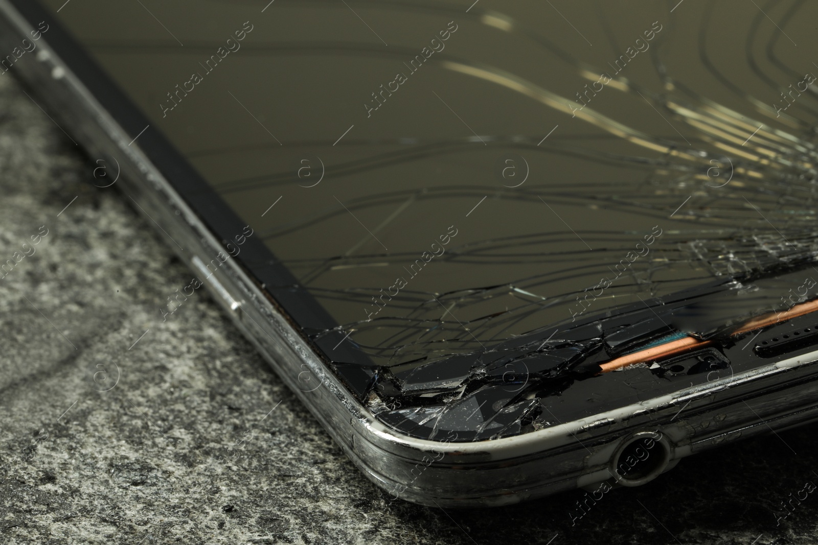 Photo of Smartphone with cracked screen on grey stone background, closeup. Device repair