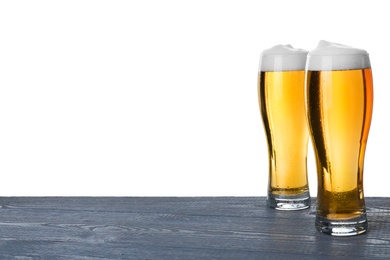 Photo of Glasses of tasty beer on blue wooden table against white background