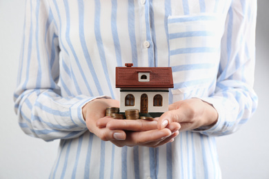 Photo of Woman holding house model and coins, closeup