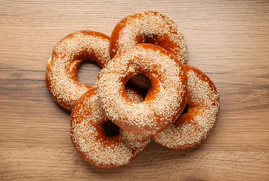 Photo of Delicious fresh bagels with sesame seeds on wooden table, flat lay