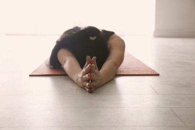 Photo of Young woman practicing relaxation pose in yoga studio, closeup