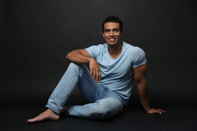 Photo of Handsome young African-American man sitting on black background