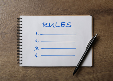 Image of Notebook with list of rules and pen on wooden table, top view