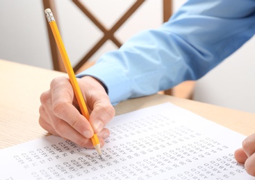 Student filling answer sheet at table, closeup