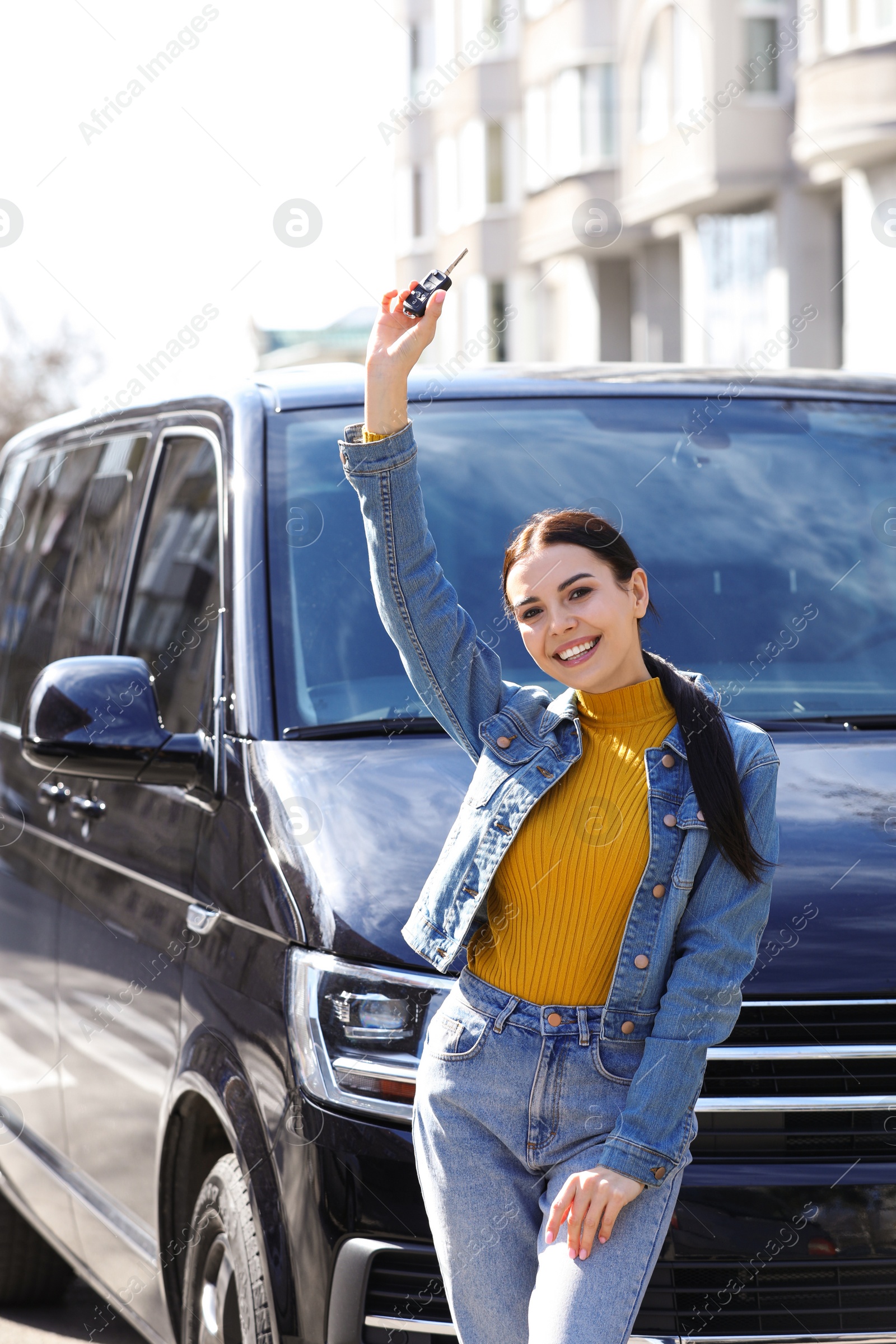 Photo of Young woman with key near car on city street. Buying new auto