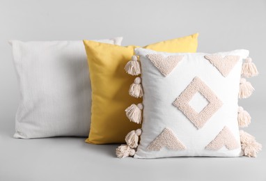 Different stylish soft pillows on grey background