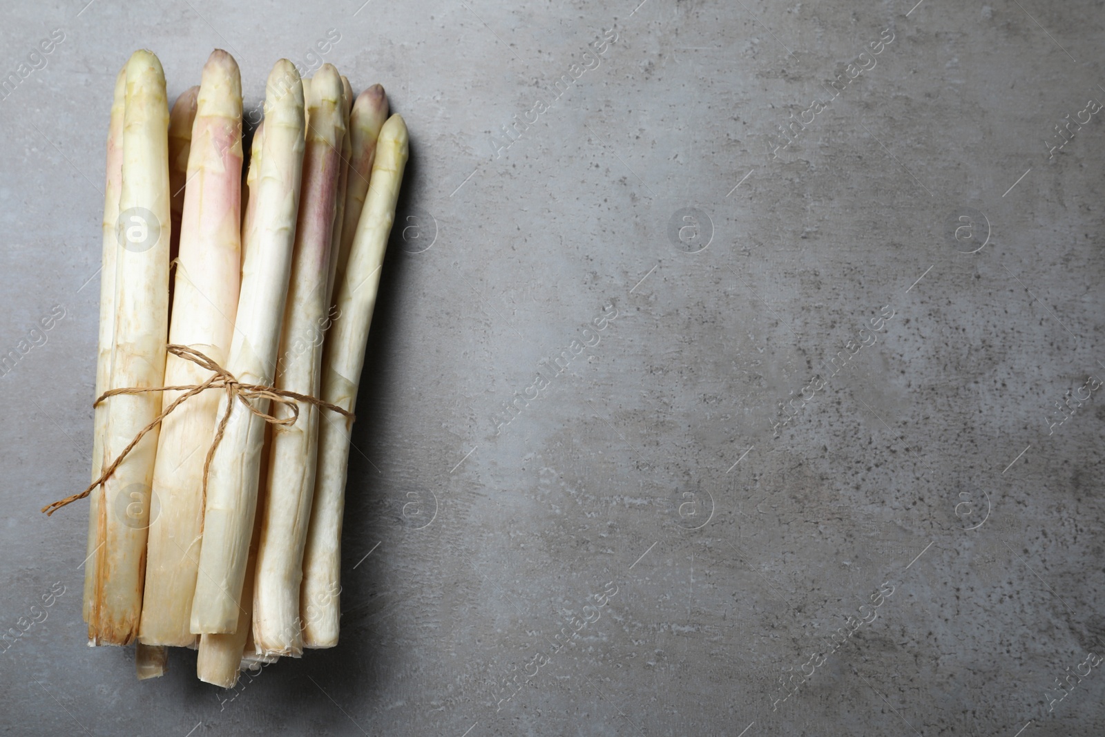 Photo of Bunch of fresh white asparagus on grey table, top view. Space for text