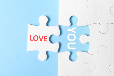 Image of Puzzle with phrase LOVE YOU on light blue background, top view