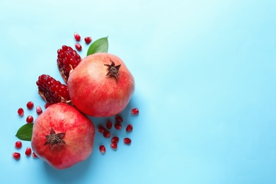 Photo of Ripe pomegranates and leaves on color background, top view with space for text