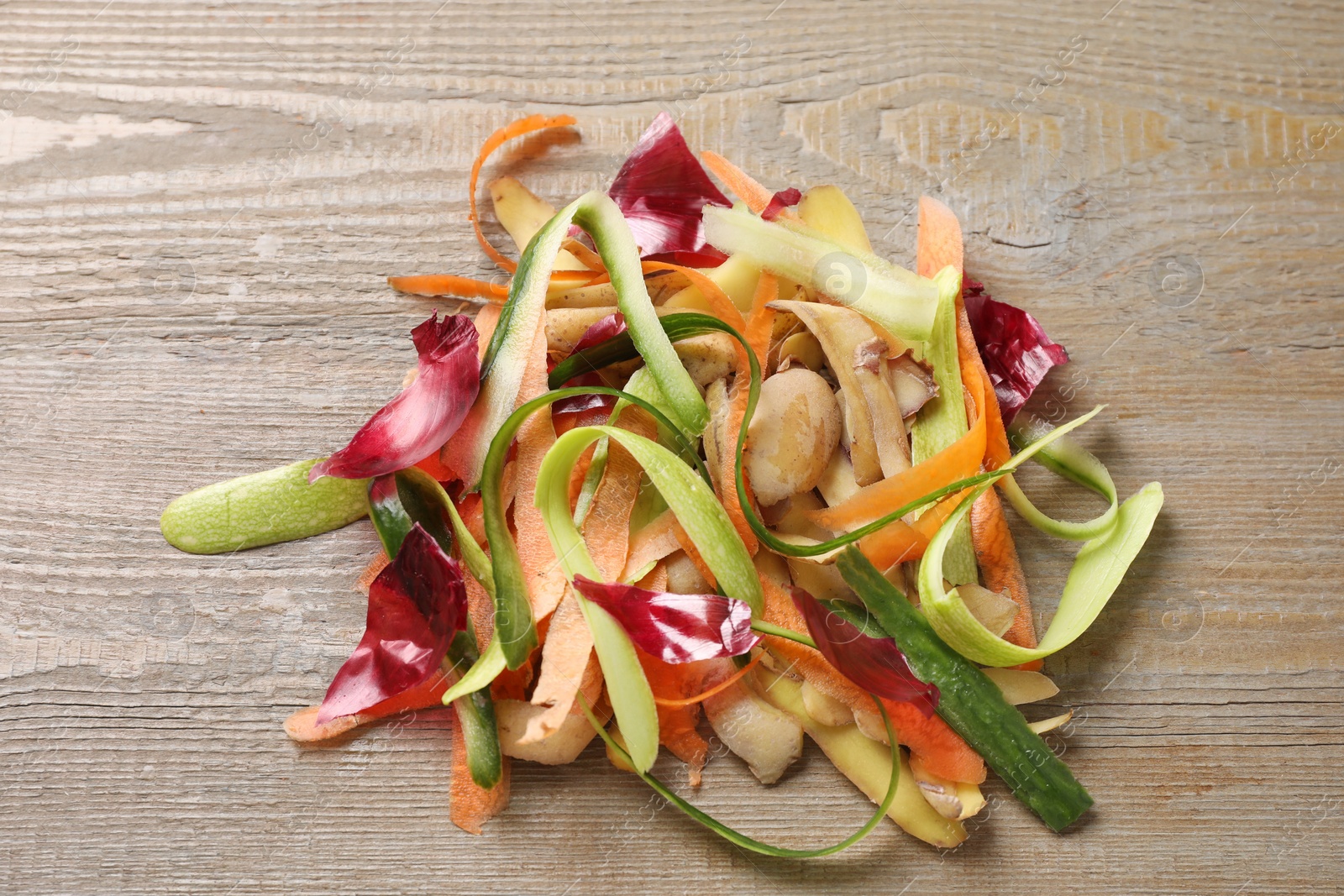 Photo of Peels of fresh vegetables on wooden table, top view