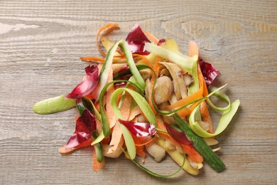 Photo of Peels of fresh vegetables on wooden table, top view