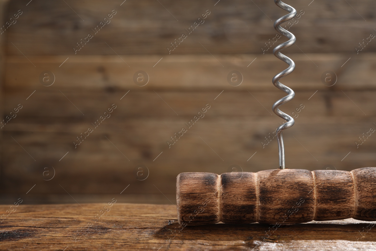Photo of One corkscrew on wooden table, closeup. Space for text