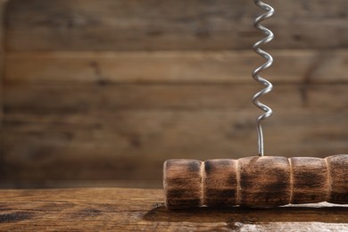 Photo of One corkscrew on wooden table, closeup. Space for text