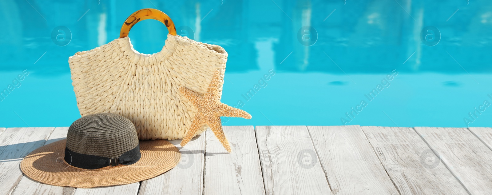 Image of Beach accessories on wooden deck near outdoor swimming pool, space for text. Banner design