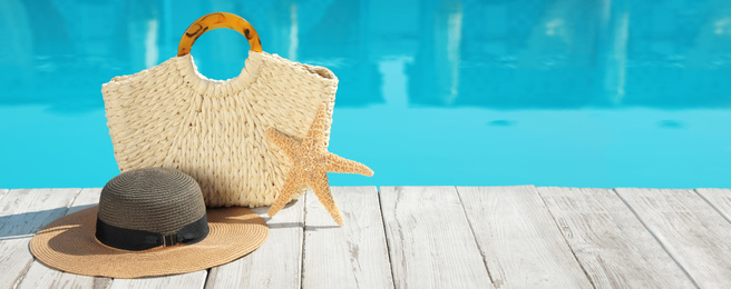Image of Beach accessories on wooden deck near outdoor swimming pool, space for text. Banner design