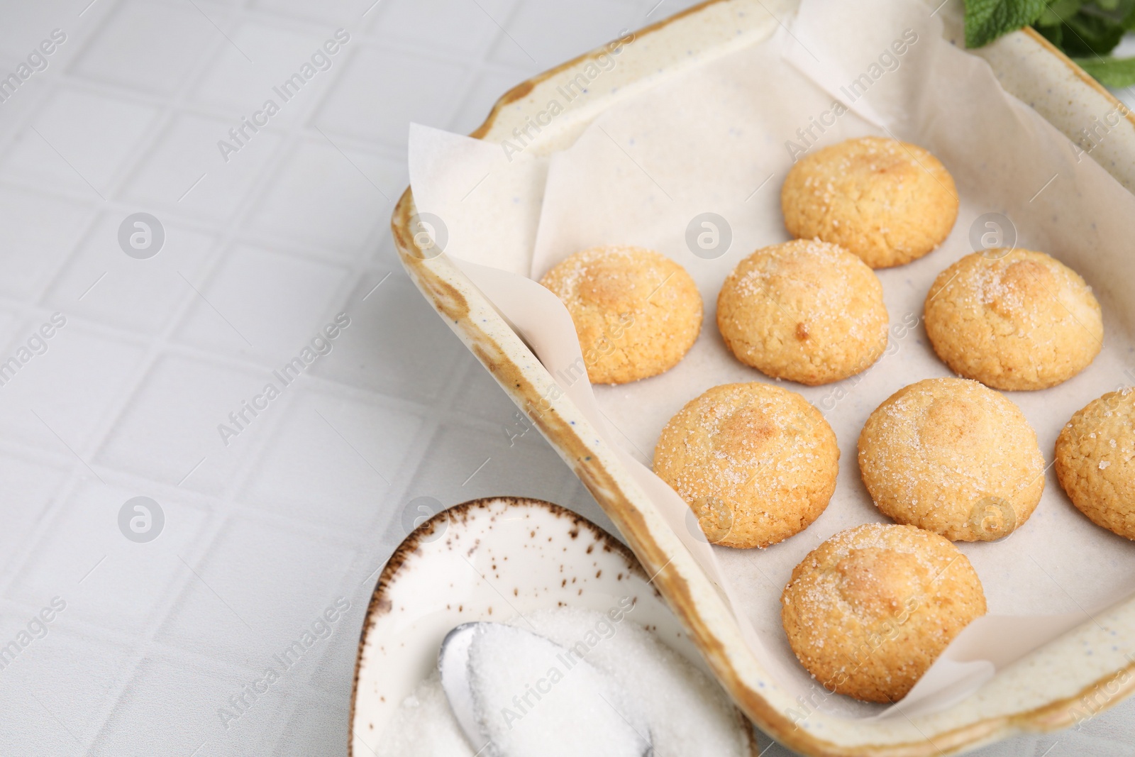 Photo of Tasty sweet sugar cookies in baking dish on white tiled table, closeup. Space for text