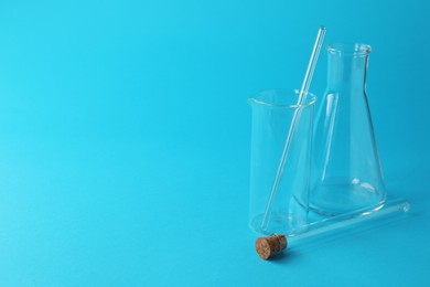 Different laboratory glassware on light blue background. Space for text