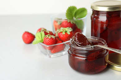 Photo of Delicious pickled strawberry jam and fresh berries on light table. Space for text