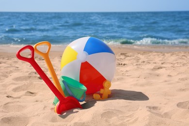 Different sand toys and beach ball near sea