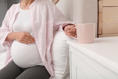 Photo of Pregnant woman drinking tea at home, closeup