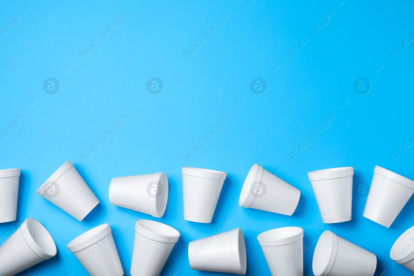 Photo of White styrofoam cups on light blue background, flat lay. Space for text