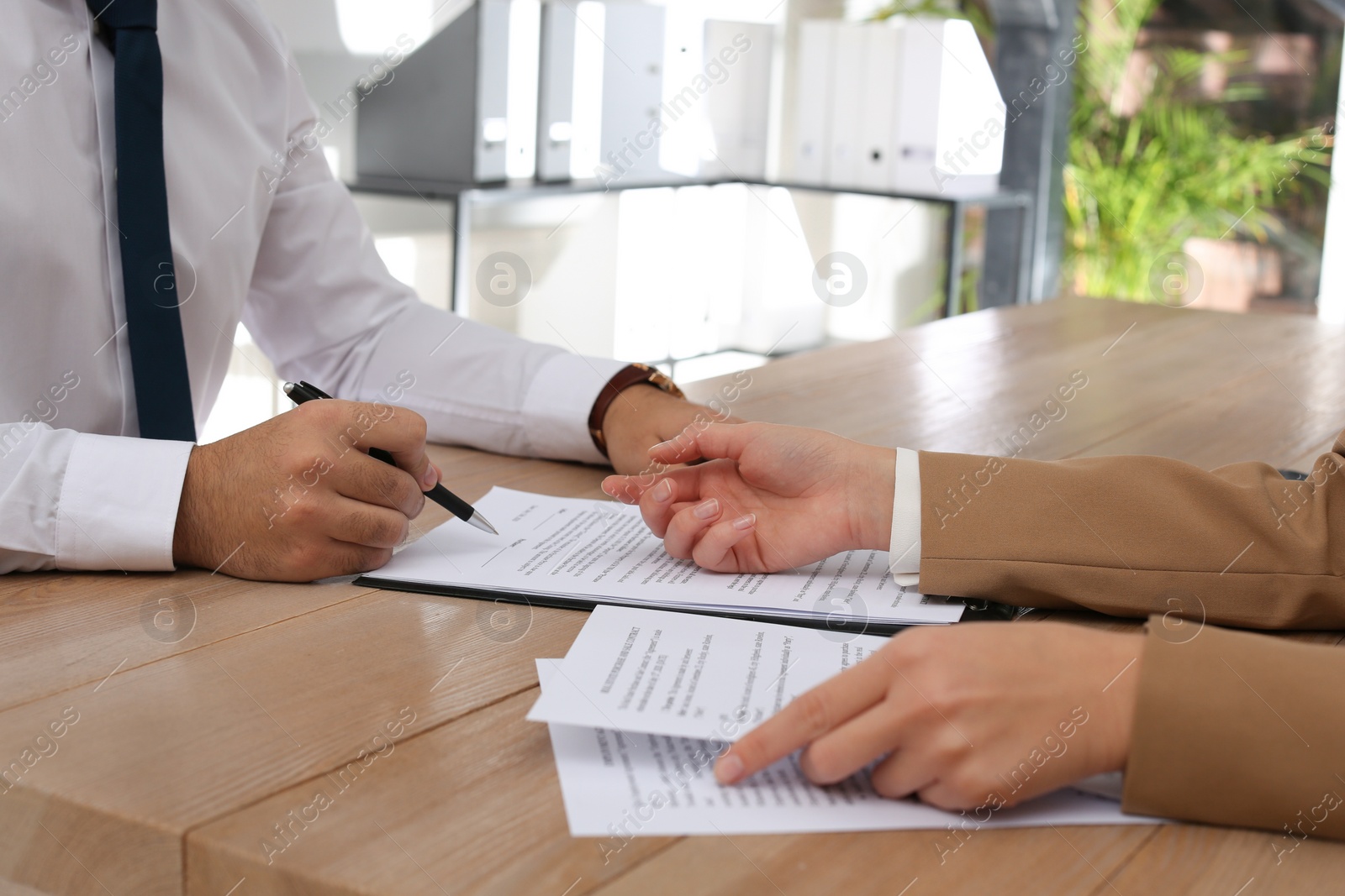 Photo of Businesspeople working with contract at wooden table indoors, closeup