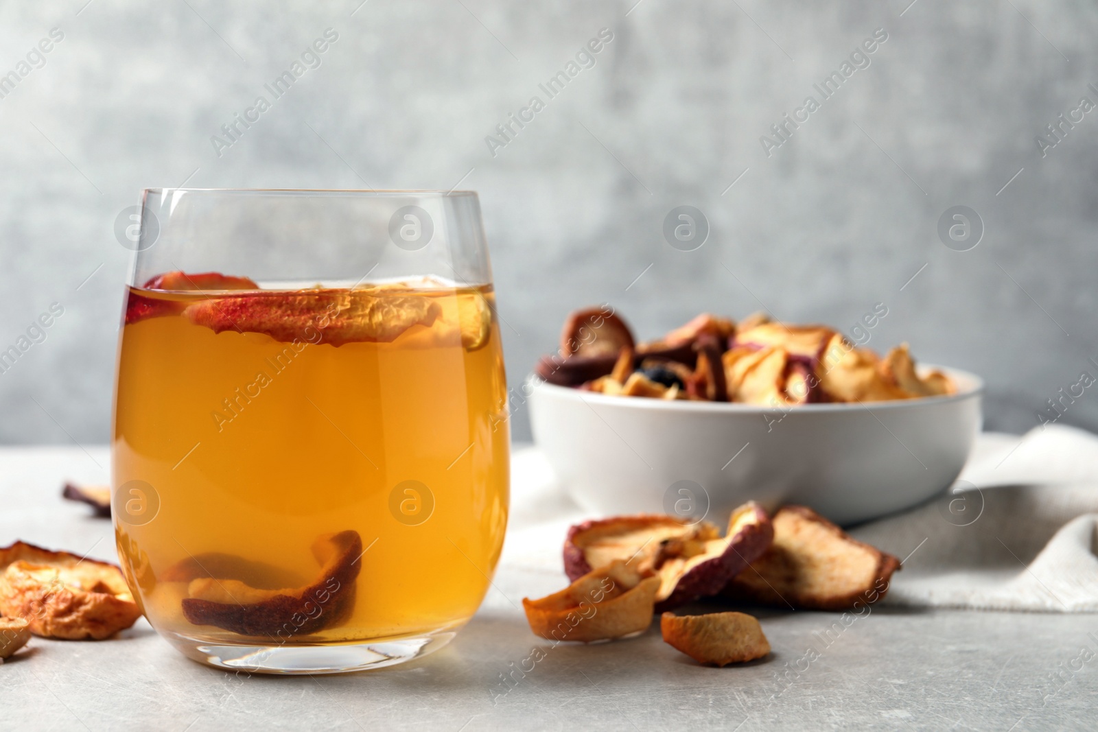 Photo of Delicious compote with dried apple slices in glass on grey table, space for text